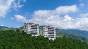 a building on top of a hill with trees at The Manor Sports and Wellness Hotel in Nāldera