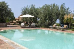a swimming pool with chairs and an umbrella at Villa Passulunara 14 by Massimo Villas in Collesano