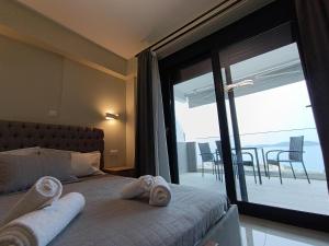 a bedroom with a bed and a large window with a balcony at ALTA MARE in Nea Peramos