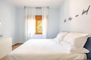 a white bedroom with a bed and a window at Appartamento del Paradosso in Spilamberto