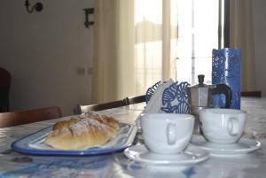 a table with a plate of croissants and cups on it at La Casa di Aldo e Maria in Marsala +6 photos