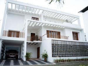 a white house with a car parked in front of it at FA Gardens in Ernakulam