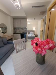 a living room with a table with a vase of pink flowers at ALTA MARE in Nea Peramos