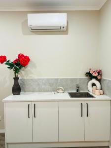 a white kitchen with a sink and red roses at Modern One Bedroom Unit with Private Entrance Near Hunua Falls in Hunua +9 photos