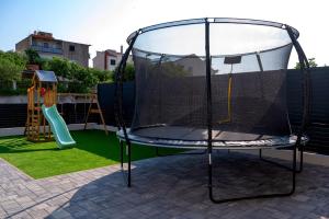 una red en un trampolín con un área de juegos en House Villa LuNi, en Brodarica