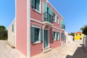 a pink building with green shutters on a street at Via Vasileia in Kattavía