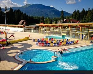 a resort with a pool with chairs and a water slide at Chata Oravice Peciská Správa TANAPu in Vitanová