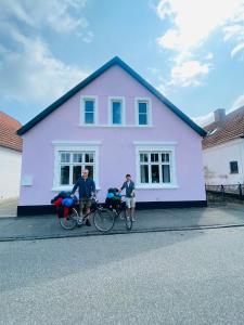two people on bikes in front of a purple house at Stub Inn Guesthouse in Stubbekøbing