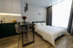 a bedroom with a bed and a desk and a kitchen at VS Apartments in Kyiv