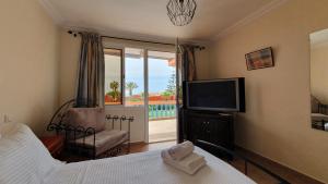 a bedroom with a bed and a tv and a balcony at Maison dans espace calme, avec piscine et plage à quelques minutes à pied in Aourir