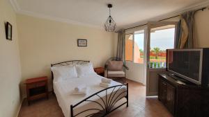 a bedroom with a bed and a tv and a balcony at Maison dans espace calme, avec piscine et plage à quelques minutes à pied in Aourir