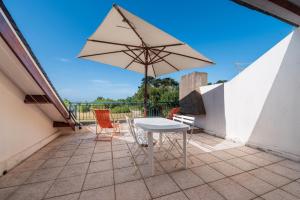 a table and chairs on a balcony with an umbrella at Appartement Arzon in Arzon