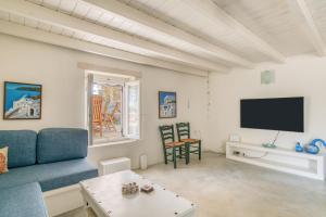 a living room with a blue couch and a tv at Great house w/ BBQ in Paros in Santa Maria