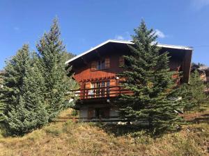 Una gran casa de madera en una colina con dos árboles. en Chalet spacieux et ensoleillé à Montgenèvre - 10 pers - 5 chambres - Quartier calme et résidentiel - FR-1-445-139, en Montgenèvre