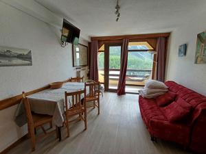 un salon avec un canapé rouge et une table dans l'établissement Studio exposé sud avec balcon, à 200m des pistes et commerces, animaux acceptés - FR-1-445-26, à Montgenèvre
