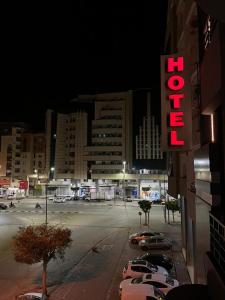 a hotel sign with cars parked in a parking lot at Pacha hotel in Sfax