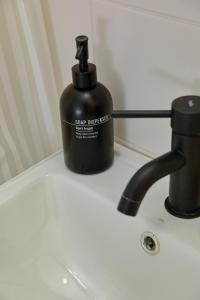 a black soap dispenser sitting on top of a sink at Comfy House in Old Town Xanthi - Meno Homes 8 in Xanthi