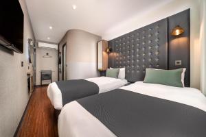 una camera d'albergo con due letti e una parete di Point A Hotel London Westminster a Londra