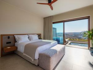 a bedroom with a large bed and a large window at Petrablu Mykonos in Elia +52 photos