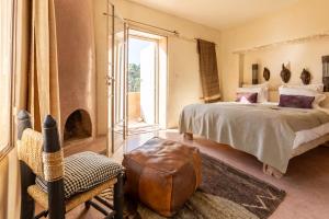 a bedroom with a bed and a chair and a window at Dar Maha - Amazing villa -heated pool 15x5M in Essaouira