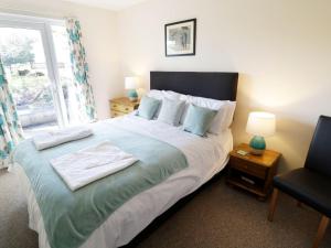 a bedroom with a bed and a chair and a window at Valley Lodge 2 in Callington +16 photos