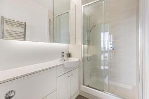 a white bathroom with a shower and a sink at Luxury Penthouse Stratford City in London +10 photos
