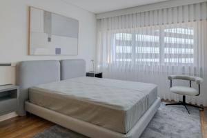 ein weißes Schlafzimmer mit einem großen Bett und einem Stuhl in der Unterkunft SONIA Travels in Matosinhos