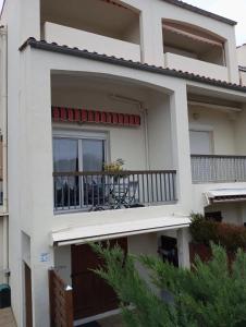 a white house with a balcony with chairs on it at Studio confortable à Dolus-d'Oléron 26 m² avec piscine in Dolus-d'Oléron