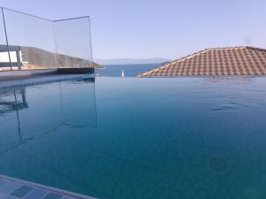 a swimming pool with clear blue water and a house at ALTA MARE in Nea Peramos