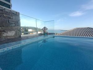 a man is standing next to a swimming pool at ALTA MARE in Nea Peramos
