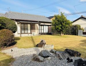 a house with rocks in front of a yard at 伊勢ゲストハウスKitai in Ise