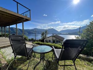 two chairs and a table with a view of a lake at Fjord view apartment in Vaksdal