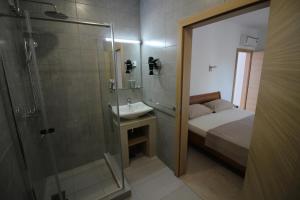 a bathroom with a shower and a bed and a sink at Apartment Umag in Umag +40 photos