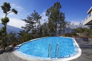 a large blue swimming pool with mountains in the background at Sinclairs Retreat Kalimpong in Kalimpong