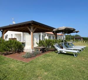 a group of chairs and an umbrella in front of a house at Villa Sabbioni in Cavallino-Treporti