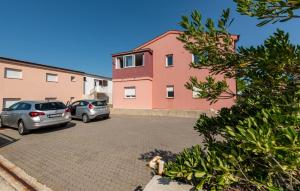 two cars parked in a parking lot next to a building at 1 Bedroom Gorgeous Apartment In Pag in Pag