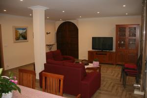 a living room with a red couch and a tv at Casa Rural Torres in Valdenoceda