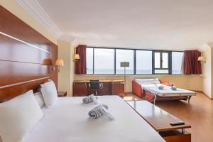 a hotel room with a bed and a desk and a bed and a table at Moon Dreams Portomagno in Aguadulce
