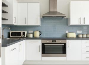 a kitchen with white cabinets and a stove top oven at 1 Bed Flat near Syon Park in Isleworth