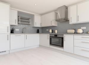 a white kitchen with white cabinets and appliances at 1 Bed Flat near Syon Park in Isleworth +1 photo