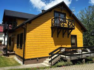 a yellow house with a balcony on the side of it at Dom Wypoczynkowy przy Szlaku OJCÓW in Ojców