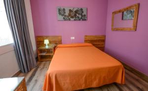 リョレート・デ・マルにあるHostal Ancoraの紫の壁のベッドルーム1室(オレンジ色のベッド1台付)