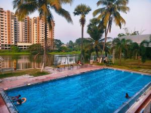 a swimming pool with palm trees and a body of water at Udaya Resort in Palakkad