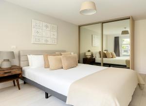 a bedroom with a large white bed and a mirror at 1 Bed Flat near Syon Park in Isleworth
