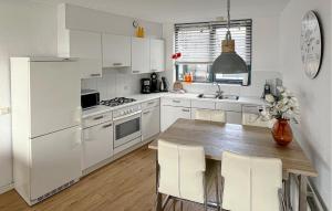 a white kitchen with a wooden table and white appliances at 3 Bedroom Cozy Home In Lemmer in Lemmer