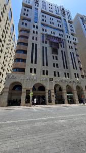 a tall building in front of a building at Artal Al Alami Hotel in Al Madinah