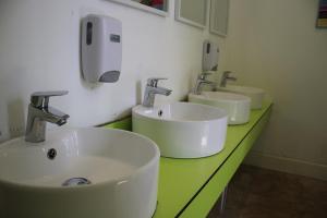 a bathroom with three sinks on a green counter at Safestay Edinburgh Cowgate in Edinburgh