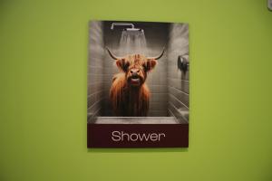 a bathroom sign with a cow in a shower at Safestay Edinburgh Cowgate in Edinburgh