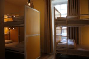 a room with three bunk beds and a mirror at Safestay Edinburgh Cowgate in Edinburgh