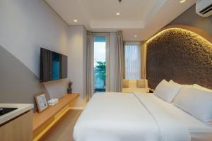 a bedroom with a large white bed and a television at Morich Suites Antasari in Jakarta